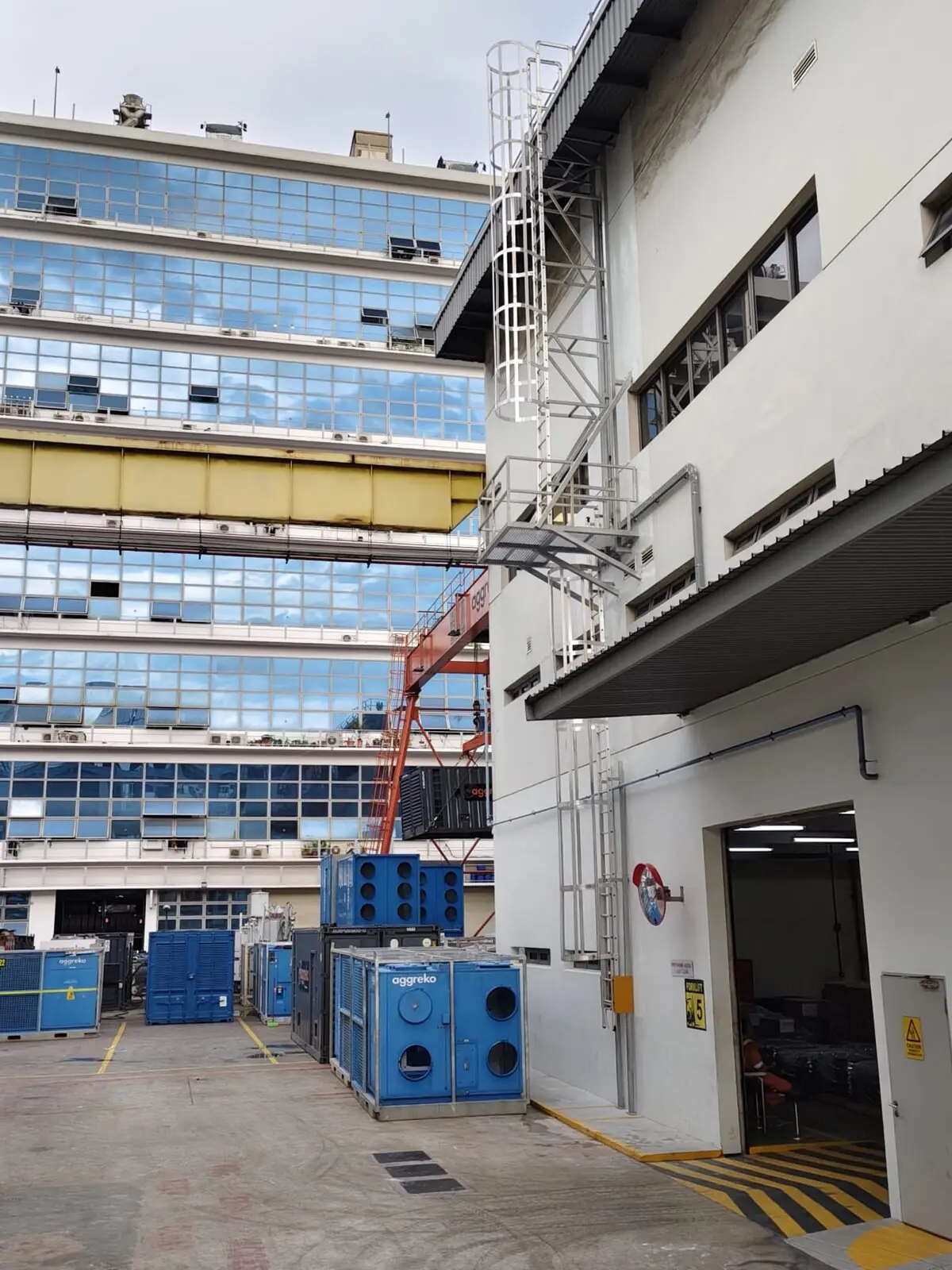 Buroh Street cat ladder rising past intermediate landing with adjacent industrial building